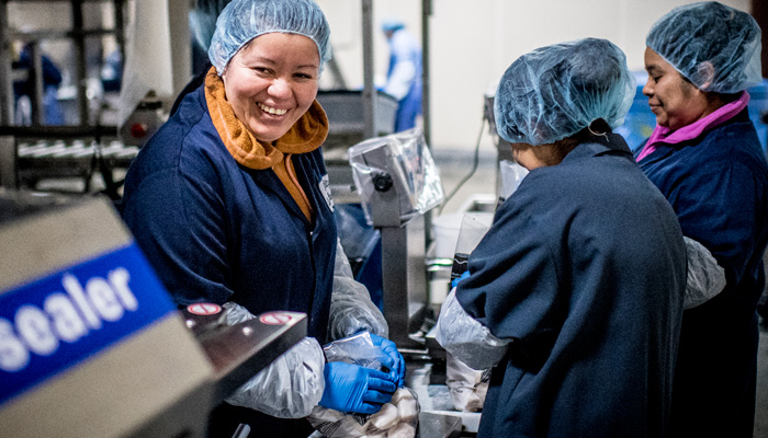A happy Premier Foods employee sealing a bag of Millennium Scallops.