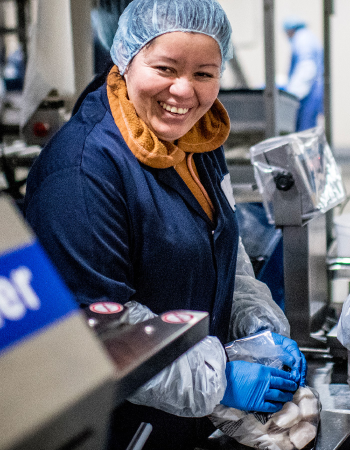 A happy Premier Foods employee sealing a bag of Millennium Scallops.